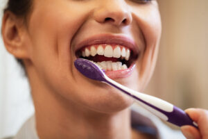 closeup woman using toothbrush while brushing teeth bathroom